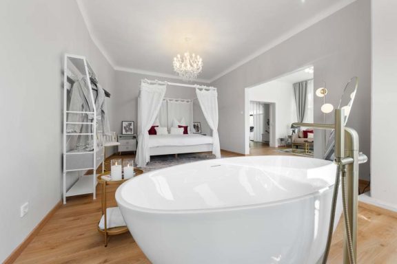 Helles, elegantes Schlafzimmer mit freistehender Badewanne und romantischem Bett.