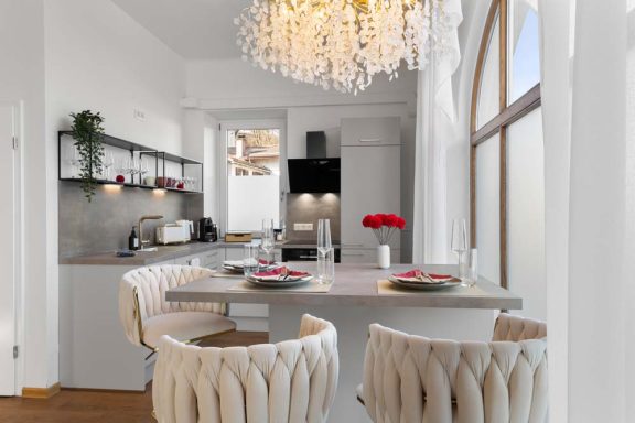 Moderne Küche mit elegantem Esstisch, Kronleuchter und frischen Rosen.