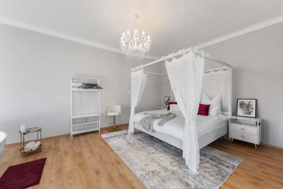 Helles Schlafzimmer mit einem Himmelbett, Teppich und moderner Dekoration.