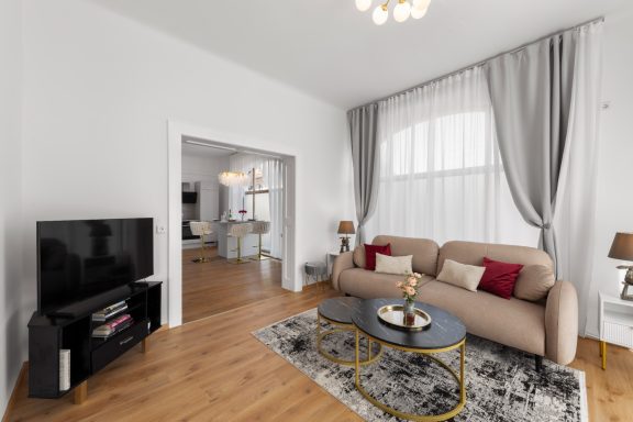 Helle, moderne Wohnzimmer mit Sofa, Teppich, Beistelltisch und Fernseher.