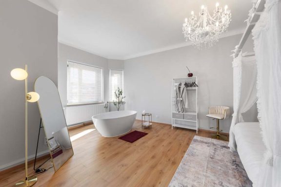 Heller, moderner Raum mit freistehender Badewanne und einem eleganten Kronleuchter.